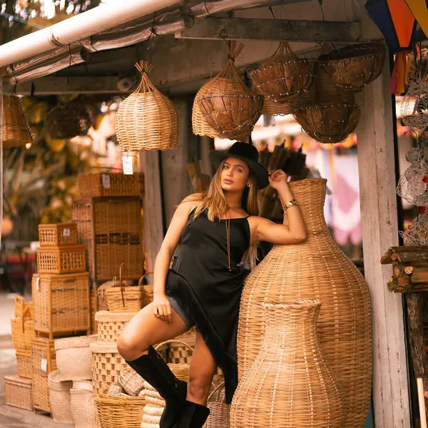 Modelo de vestido preto e bota de cano alto preta em cena de feira