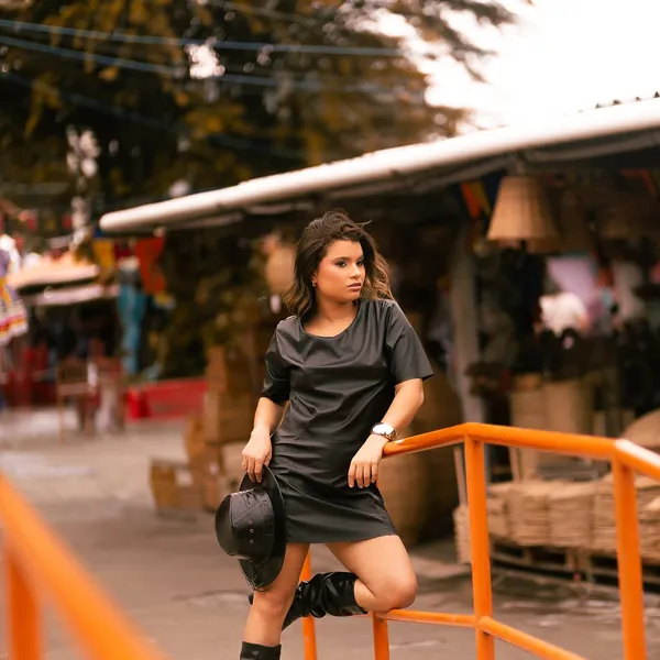 Modelo de vestido preto com bota de cano médio slouch
