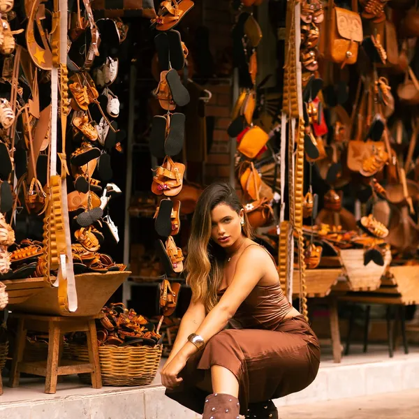 Modelo com bota marrom de tachas em frente a banca de artesanato em couro